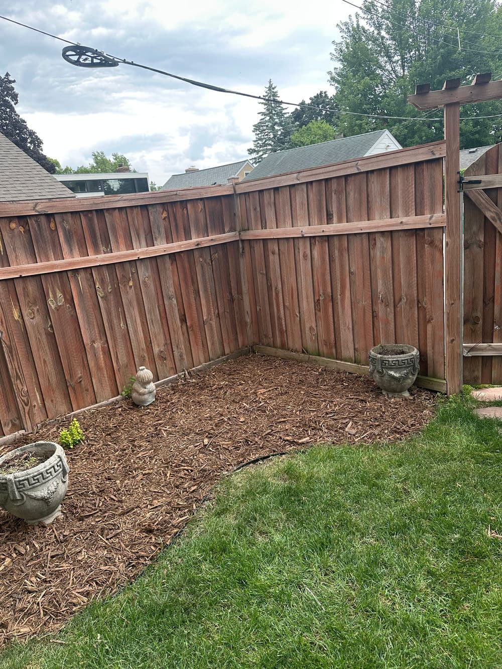 Serene backyard corner with wooden fence, gravel landscaping, and decorative stone planters.